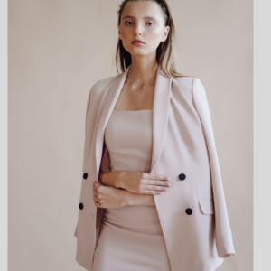 Model wearing a blush pink fitting dress with an attractive oversized blazer, exhibiting Riti design Designer's minimalist luxury design.