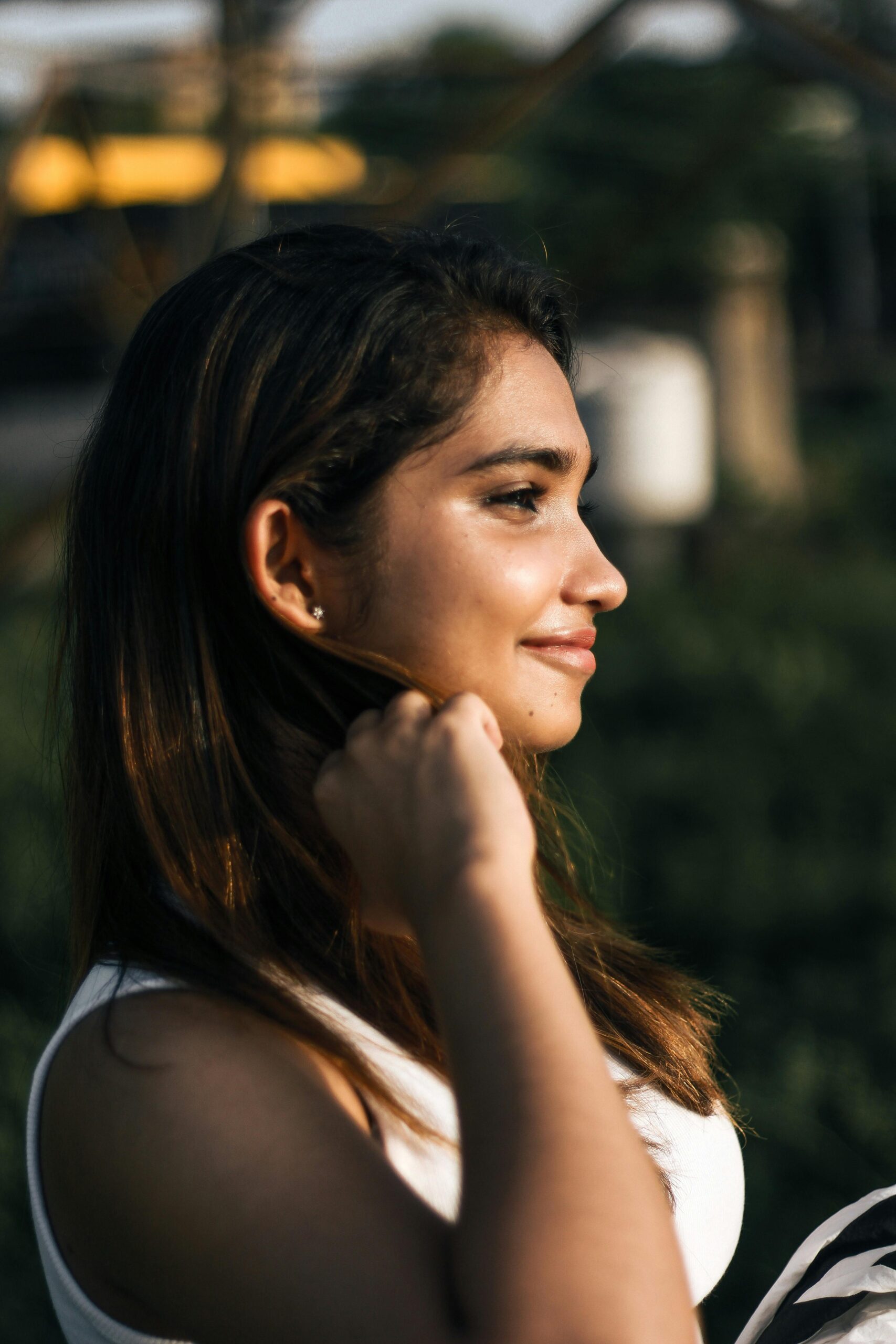 Profile portrait of a young woman smiling in the summer sun in Sweden, displaying joy.